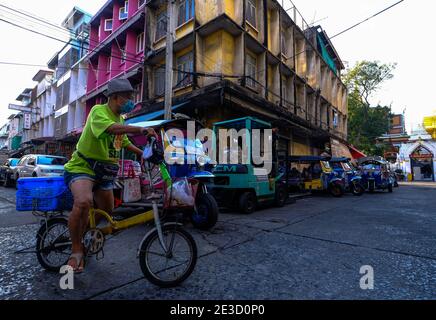 Ein Mann fährt mit dem Fahrrad an einer Gruppe geparkter Tuk Tuks in Chinatown, Bangkok, Thailand vorbei Stockfoto