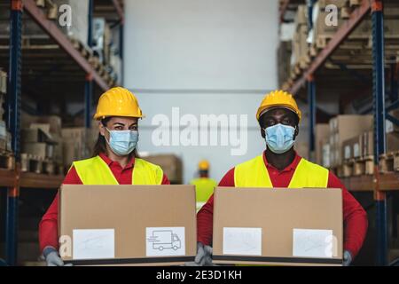 Das Team arbeitet im Lager und lädt die Lieferkisten mit dem Gesicht Chirurgische Maske während Corona Virus Pandemie - Logistik und Industrie Konzept Stockfoto