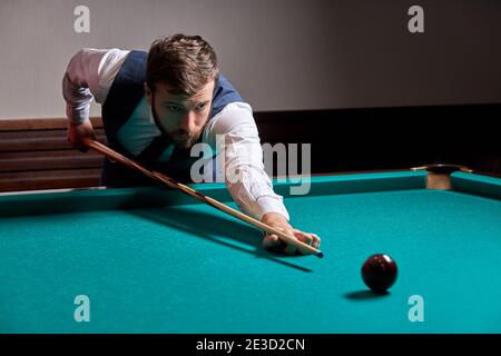 Mann, der Arm auf Billardtisch hält, Snooker-Spiel spielt oder sich darauf vorbereitet, Poolbälle zu schießen. Sportspiel Snooker Billard Stockfoto