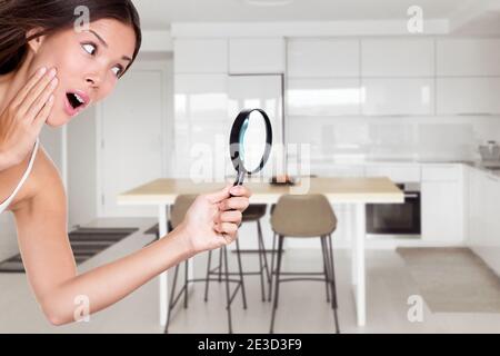 Hausbesitzer Frau Inspektion Küche mit Lupe auf der Suche nach Geräten oder Einkaufen Verkauf für Innenarchitektur Möbel Dekoration. Asiatische Mädchen Stockfoto