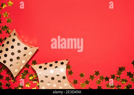 Konfetti mit goldenem Stern und Geschenkschachteln auf rotem Papierhintergrund. Valentinstagskonzept. Flache Lay-Ansicht und Draufsicht, Vorlage für Kopierraum Stockfoto