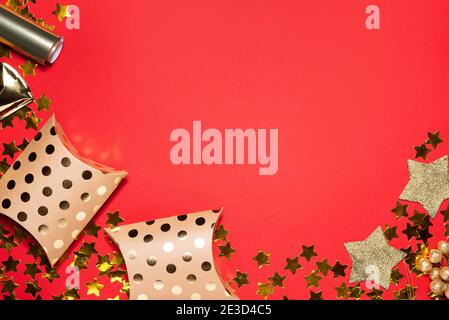 Konfetti mit goldenem Stern und Geschenkschachteln auf rotem Papierhintergrund. Valentinstagskonzept. Flache Lay-Ansicht und Draufsicht, Vorlage für Kopierraum Stockfoto