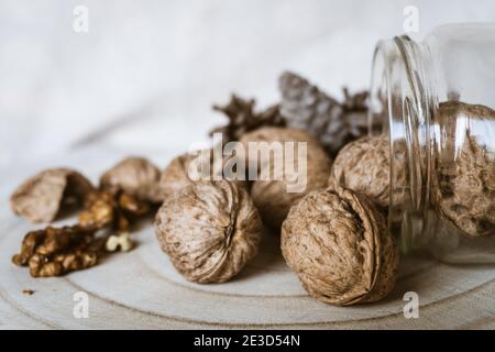 Nahaufnahme von frischen und ganzen Walnüssen auf einem rustikalen Holzbrett. Stockfoto