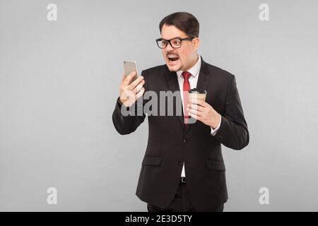 Emotionaler Chef schreit den Gesprächspartner an. Indoor, Studioaufnahme, isoliert auf grauem Hintergrund Stockfoto