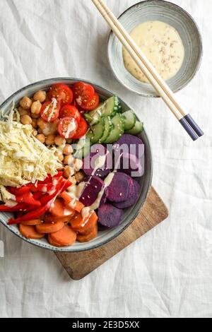 budha Schüssel mit violetten Batata, Paprika, Kohl, Süßkartoffeln, Kichererbsen, Gurken auf der weißen Leinentischdecke Stockfoto