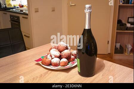 Traditionelles Silvesteressen in Holland: Frittierte Donut-Bälle (holländisch: Oliebollen) mit Puderzucker und Champagner bestreut Stockfoto