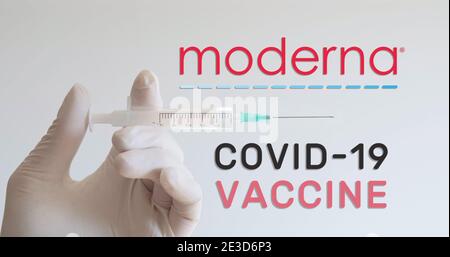 Hand mit Handschuh hält Spritze neben Moderna Logo, einem der Unternehmen, das einen Covid-19 (Coronavirus) Impfstoff entwickelt. Wien, Österreich - 18. Januar 20 Stockfoto