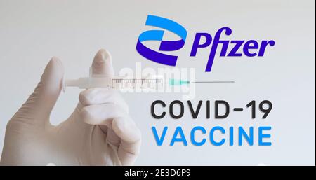 Hand mit Handschuh hält Spritze neben dem Pfizer Logo, einem der Unternehmen, das einen Covid-19 (Coronavirus) Impfstoff entwickelt. Wien, Österreich - 18. Januar 202 Stockfoto