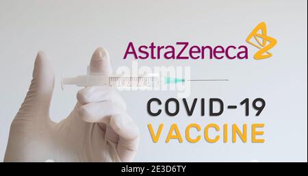 Hand mit Handschuh hält die Spritze neben dem AstraZeneca-Logo, einem der Unternehmen, das einen Covid-19 (Coronavirus)-Impfstoff entwickelt. Wien, Österreich - Januar 18 Stockfoto