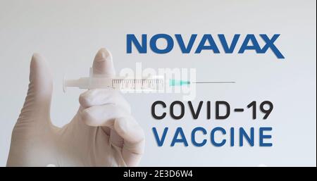 Hand mit Handschuh hält die Spritze neben dem Novavax-Logo, einem der Unternehmen, das einen Covid-19 (Coronavirus)-Impfstoff entwickelt. Wien, Österreich - 18. Januar 20 Stockfoto