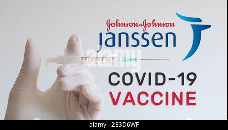 Hand mit Handschuh hält Spritze neben Janssen, Johnson und Johnson Logos, zwei der Unternehmen, die einen Covid-19 (Coronavirus) Impfstoff entwickeln. Wien, Au Stockfoto