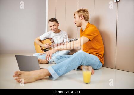 Glücklich Gay Paar sitzt auf dem Boden und mit Laptop Stockfoto