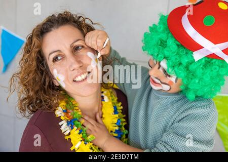 Kleines Kind malte seine Mütter Gesicht an Karneval Stockfoto