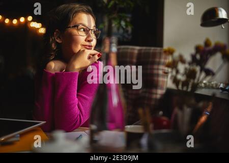 Glückliche, hübsche Frau, die die Aussicht vom Fenster genießt Sitzen im Café und arbeiten Stockfoto