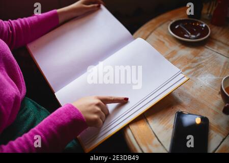 Nahaufnahme der weiblichen Hände halten Menü und gehen zu Geben Sie eine Bestellung im Kaffeehaus auf Stockfoto