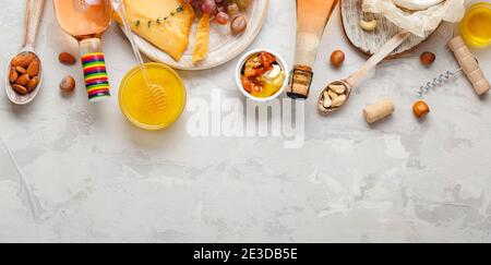 Rosa Weinkomposition auf hellgrauem rustikalem Betonhintergrund mit Kopierraum. Rosenwein Flasche Käse Nüsse und rosa Trauben, Honig. Camembert-Käse Stockfoto
