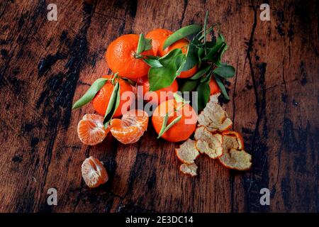 Klementinen mit Blättern auf einem alten Holztisch Stockfoto