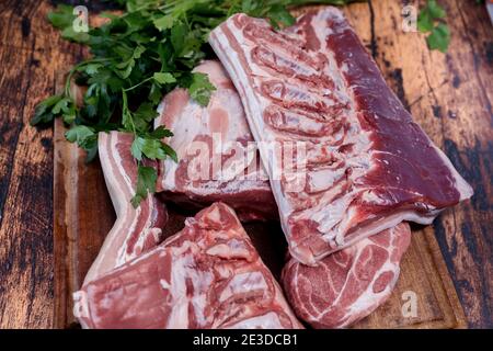 Frischer Schweinebauch auf einem gebrauchten Schneidebrett, auf dem er ruht Ein alter Holztisch Stockfoto