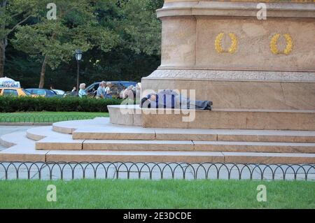 Obdachloser schläft auf der Statue zum Central Park New York USA Tramp New York City schläft vor der Parkstatue Stufen Marmorparks Stockfoto