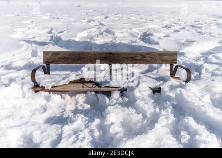 High-Winkel-Aufnahme einer kleinen Holzbank in einem Feld im Schnee bedeckt Stockfoto