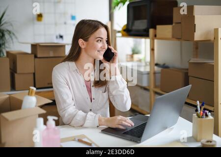 Junge Frau Dropshipper mit Laptop zu Hause arbeiten, Coronavirus Konzept. Stockfoto