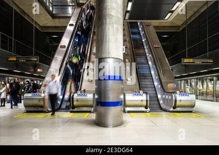 Pendler steigen über die Rolltreppen in die moderne U-Bahnstation Canary Wharf der Jubilee Line der Londoner U-Bahn. Stockfoto