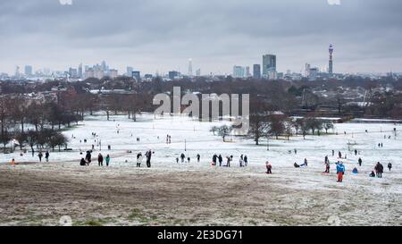 London, England, UK - 10. Dezember 2017: Familien spielen mit Schlitten auf Primrose Hill an einem seltenen Schneetag in London, mit Wahrzeichen der City of Londo Stockfoto