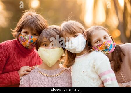 Portrait von Kindern im Schulalter in geschützten Gesichtsmasken gehen Im Herbst Park bei Sonnenuntergang Stockfoto