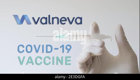 Hand mit Handschuh hält die Spritze neben dem Valneva-Logo, einem der Unternehmen, das einen Covid-19-Impfstoff (Coronavirus) entwickelt. Wien, Österreich - 18. Januar 20 Stockfoto