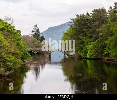 Der River Oice fließt unter einer hölzernen Fußgängerbrücke in Loch Ness bei Fort Augustus in den Highlands von Schottland. Stockfoto