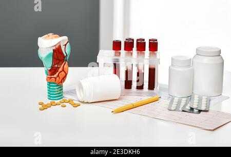 Diagnose von Schilddrüsenerkrankungen. Anatomisches Modell der Schilddrüse, Blut für die Analyse in Reagenzgläsern und Pillen für die endokrinologische Behandlung, Nahaufnahme Stockfoto