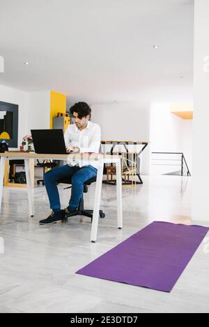 Junger mexikanischer Mann meditiert und macht Yoga im Büro in Lateinamerika Stockfoto
