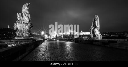 Karlsbrücke und Prager Burg in der Weihnachtszeit bei Nacht. Prag, Tschechische Republik. Schwarzweiß-Bild. Stockfoto