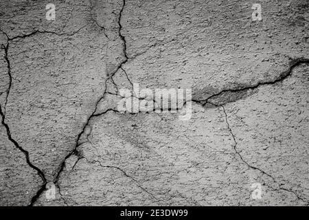 Nahaufnahme von rissiger und verwitterter Zementwand, Vorderansicht. Hochauflösender texturierter Hintergrund im Vollformat in Schwarzweiß. Stockfoto
