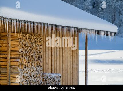 Holzhütte mit Schnee bedeckt und perfekt aufgereihte Eiszapfen Stockfoto