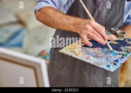 Künstler mischen Farben auf Palette halten in der Hand Nahaufnahme. Kreativität, Kunstkonzept Stockfoto