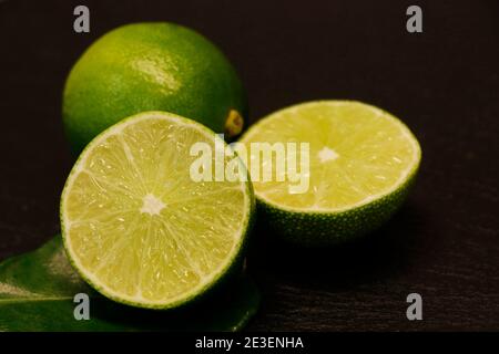 Frisch geschnittene grüne Limetten auf schwarzem Hintergrund Stockfoto