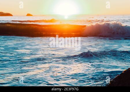 Wellenbrechung auf den großen Felsbrocken der Küste von Camps Bay in Kapstadt, Südafrika Stockfoto