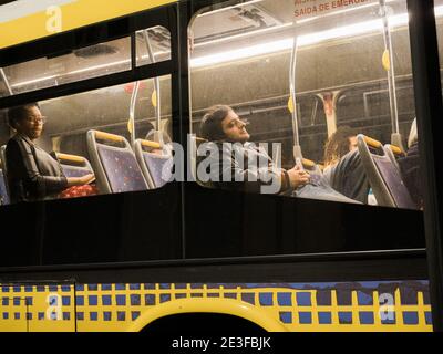 Lissabon, Portugal - 10. Feb 2018: Seitenansicht einer entspannten portugiesischen Frau und eines Mannes in einem gelben Bus mit öffentlichen Verkehrsmitteln Stockfoto