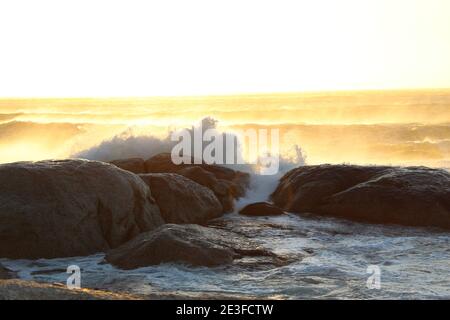 Wellenbrechung auf den großen Felsbrocken der Küste von Camps Bay in Kapstadt, Südafrika Stockfoto