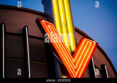 Vintage Neon Leuchtrohre bilden Buchstaben V auf der metallischen Dach mit dunkel blau warmen Farbe Oberlicht im Hintergrund Stockfoto