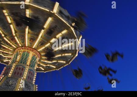 Schaukelfahrt auf der Messe, die sich in der Dämmerung dreht Stockfoto