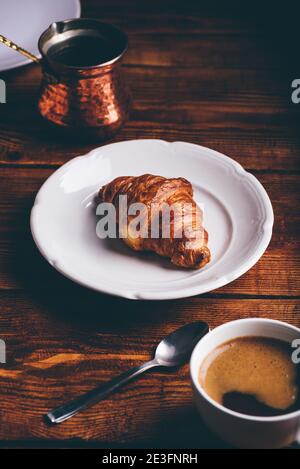 Tasse türkischer Kaffee und Croissant auf weißem Teller für Frühstück Stockfoto