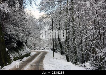 Holprige und schlecht gepflasterte Straße Weg auf Berg Winterschnee Weißer Feldweg im Wald in der toskana Stockfoto