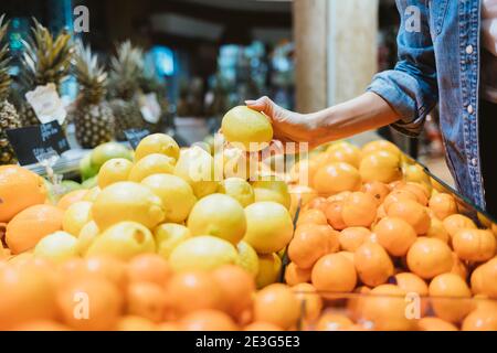 Die Hand der Frau hält eine Orange in der Nähe des Ladens Stockfoto