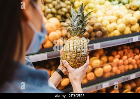 Nahaufnahme einer Brünette Frau wählt eine Ananas in der Speichern Stockfoto