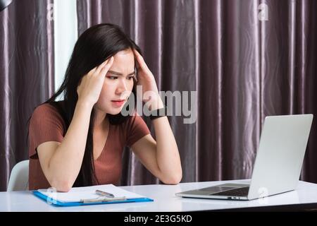 Arbeit von zu Hause, ermüdet oder Belastung Asian Business junge schöne Frau auf dem Schreibtisch Arbeitsplatz Gefühl müde gestresst Hand halten Kopf nach langem SED sitzen Stockfoto