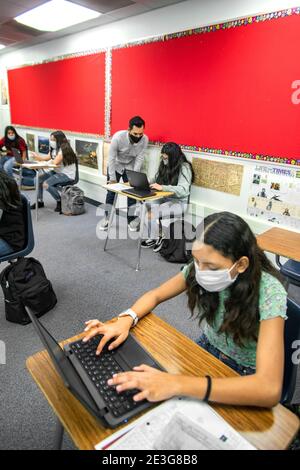 Ein zweisprachiger hispanischer Lehrer für Sozialstudien der siebten Klasse, der aufgrund der Coronavirus-Pandemie eine Gesichtsmaske waring, unterrichtet seine Klasse in Spanisch A Stockfoto