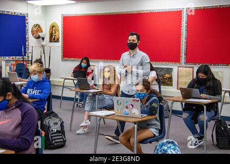 Ein zweisprachiger hispanischer Lehrer für Sozialstudien der siebten Klasse, der aufgrund der Coronavirus-Pandemie eine Gesichtsmaske waring, unterrichtet seine Klasse in Spanisch A Stockfoto