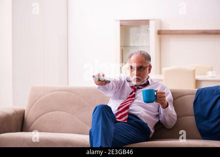 Leitender männlicher Chef-Angestellter, der zu Hause Fernsehen schaut Stockfoto